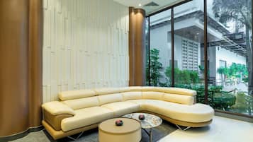 Ein modernes Wohnzimmer mit einer gebogenen Couch, einem runden Couchtisch und einem großen Fenster mit Blick ins Freie.