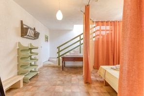 A room with a bed, a bench, a staircase, and a wall-mounted rack. - Casa Tarantini – The House of Capers and Grapes (Corsano)