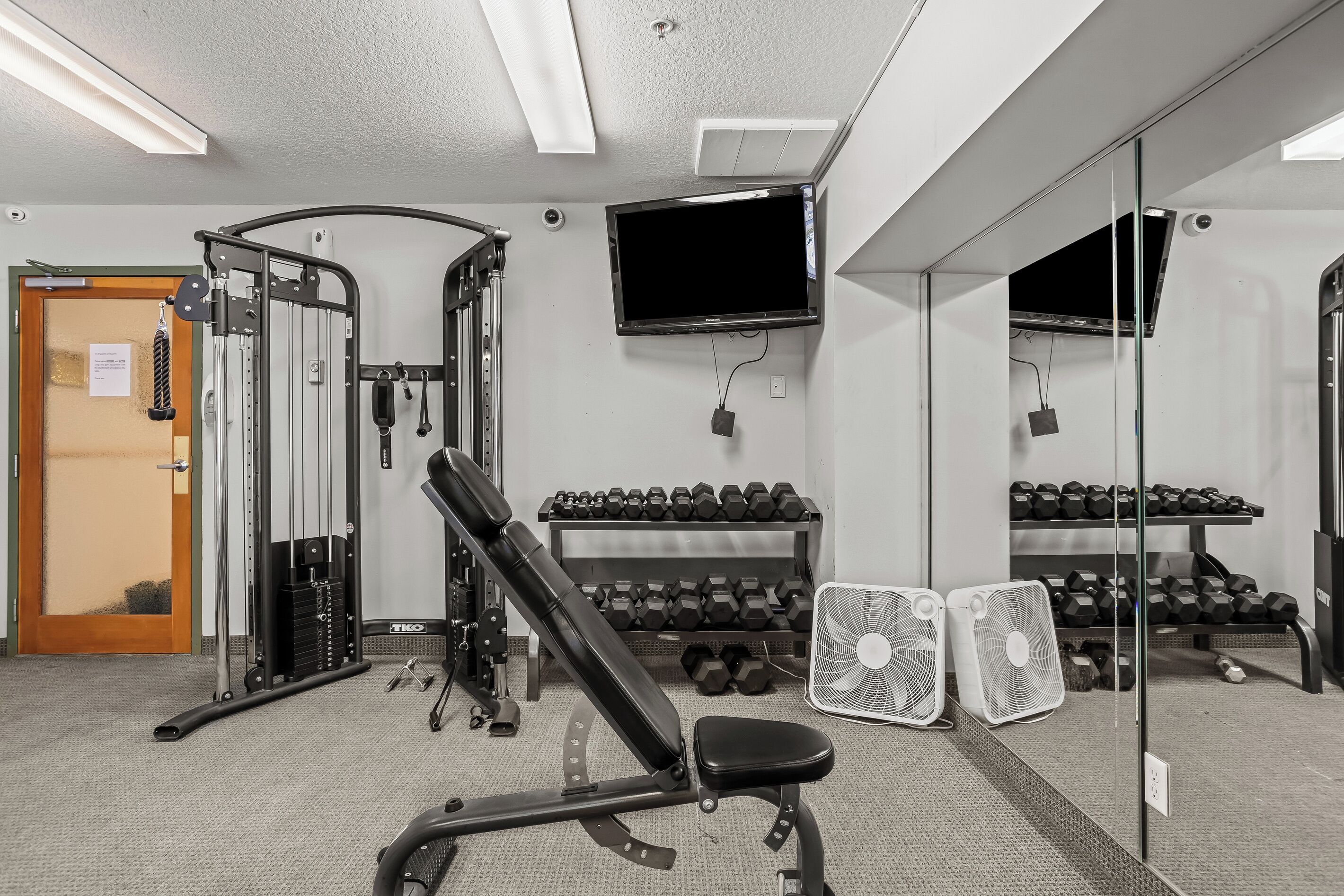 A gym with exercise equipment, a television, and a mirror.