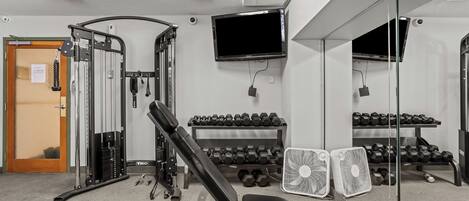 Une salle de sport équipée de matériel d’exercice, d’un téléviseur et d’un miroir.