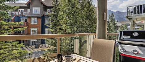 A balcony with a wooden table, two black mugs, and a deck of playing cards.