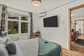A modern bedroom with a bed, a desk, and a TV mounted on the wall. - Quaint Canmore Basecamp | Views (Canmore)
