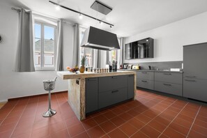 A modern kitchen with grey cabinets, a central island, and a large window with curtains. - LiT LiVING Grünstadt (Grünstadt)