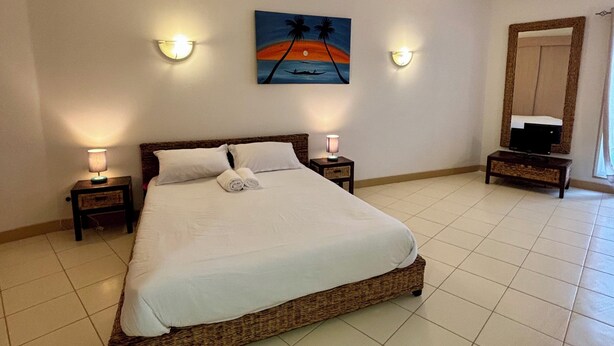 Una habitación de hotel con una cama grande, dos lámparas de noche, un cuadro en la pared y un televisor sobre una mesita.
