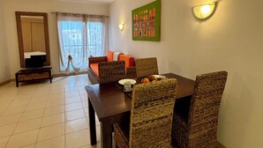 Un comedor con una mesa, sillas y un televisor sobre un mueble.
