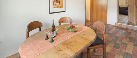 Un coin repas avec une table en bois, des chaises, un vase en verre contenant des fleurs et un tableau encadré accroché au mur.