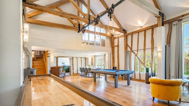 Una habitación amplia con mesa de billar, un sillón amarillo y una mesa de futbolín.
