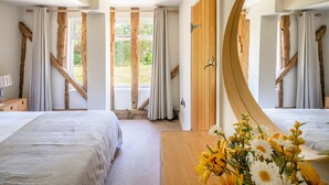 Un dormitorio con dos camas, una puerta de madera y vistas al exterior.