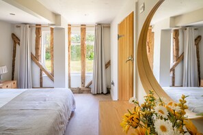 A bedroom with two beds, a wooden door, and a view of the outdoors. - Wolmers Barn, Stonham Aspal, Suffolk (Stonham Aspal)