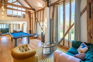 A spacious room with a pool table, a comfortable sofa, and large windows offering a view of the outdoors. - Wolmers Barn, Stonham Aspal, Suffolk (Stonham Aspal)