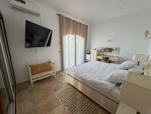 Een slaapkamer met een bed, een televisie, een bureau en een stoel.