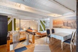 A room with a wooden staircase, a bed, a table with chairs, and a painting on the wall. - Mammut Loft Apartment (Balve)