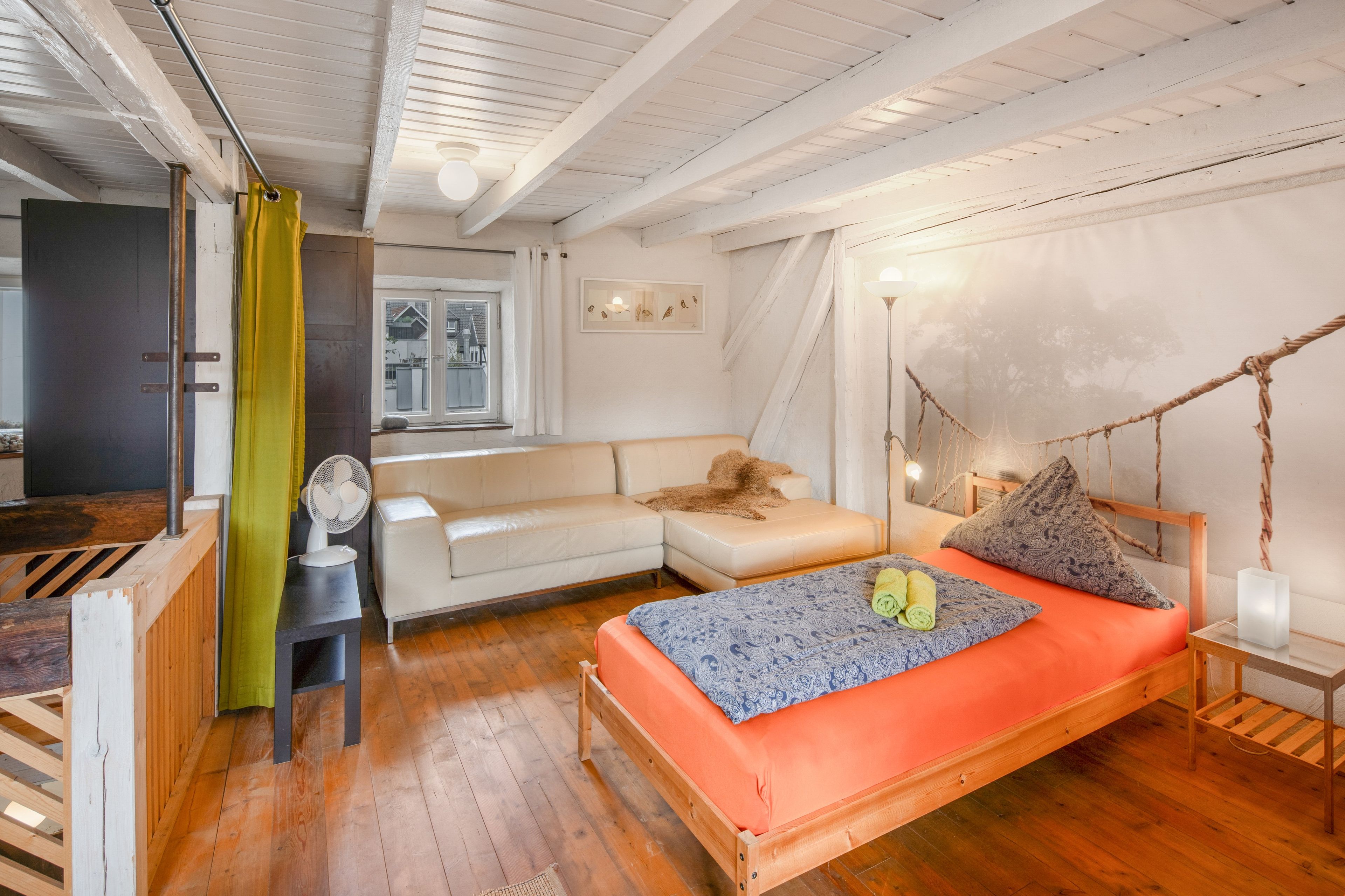 Ein Schlafzimmer mit einem Bett, einem Nachttisch, einer Lampe, einem Fenster und Blick ins Freie.
