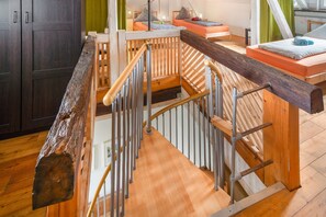 A wooden staircase with metal railings leading to a bedroom with a bed and a window. - Mammut Loft Apartment (Balve)
