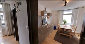 Et moderne køkken med indbyggede apparater, et spiseområde med et bord og stole, samt et vindue med gardiner.