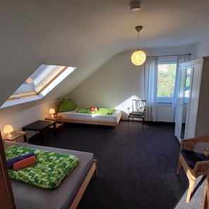 Et lille værelse med en køjeseng, et skrivebord, en stol og et vindue med gardiner.