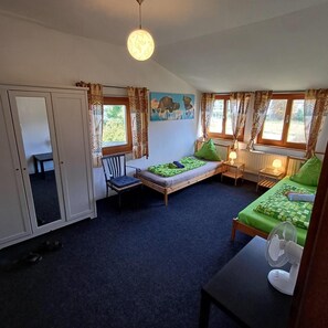 Una habitación con cama, una silla, una mesa y un ventilador.