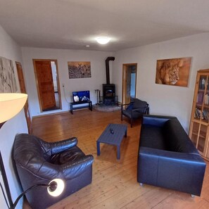 Una sala de estar con chimenea, sofá de cuero, sillón y estantería.