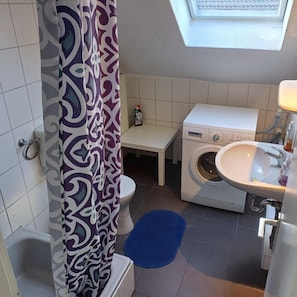 Un baño pequeño con lavadora, lavamanos e inodoro.