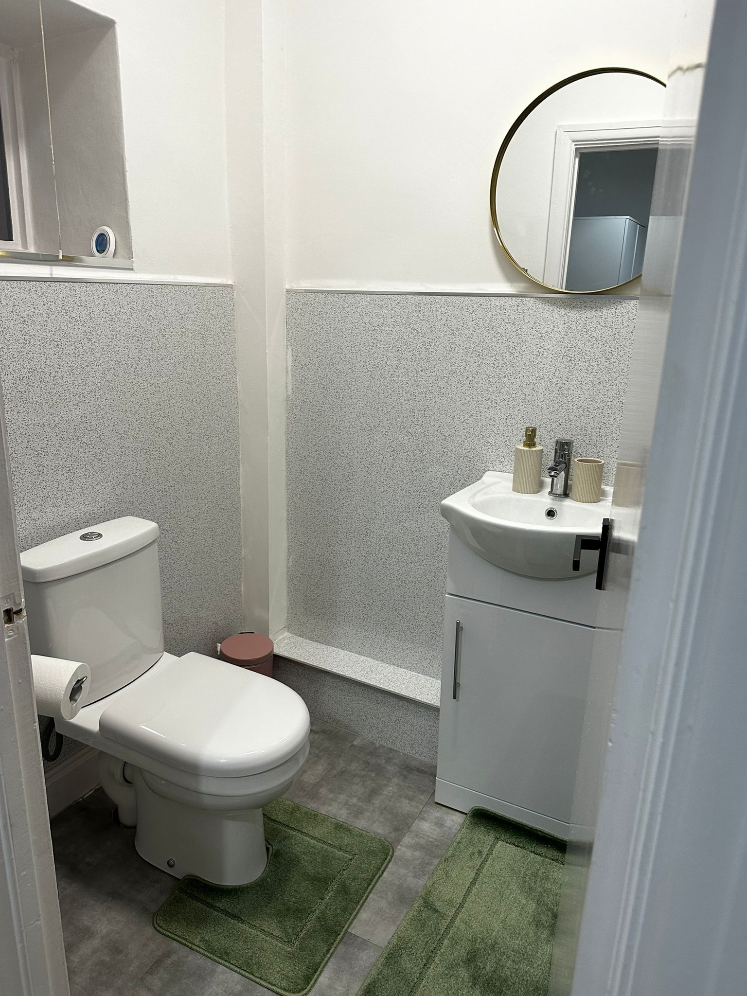 A compact bathroom with a toilet, sink, and a small trash bin.