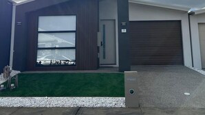 Uma casa moderna de dois andares com uma porta de garagem grande, número '28' visível na porta e um gramado bem cuidado.