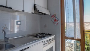 Eine Küche mit einem Gasherd, einem Spülbecken und einem Fenster mit Vorhang.