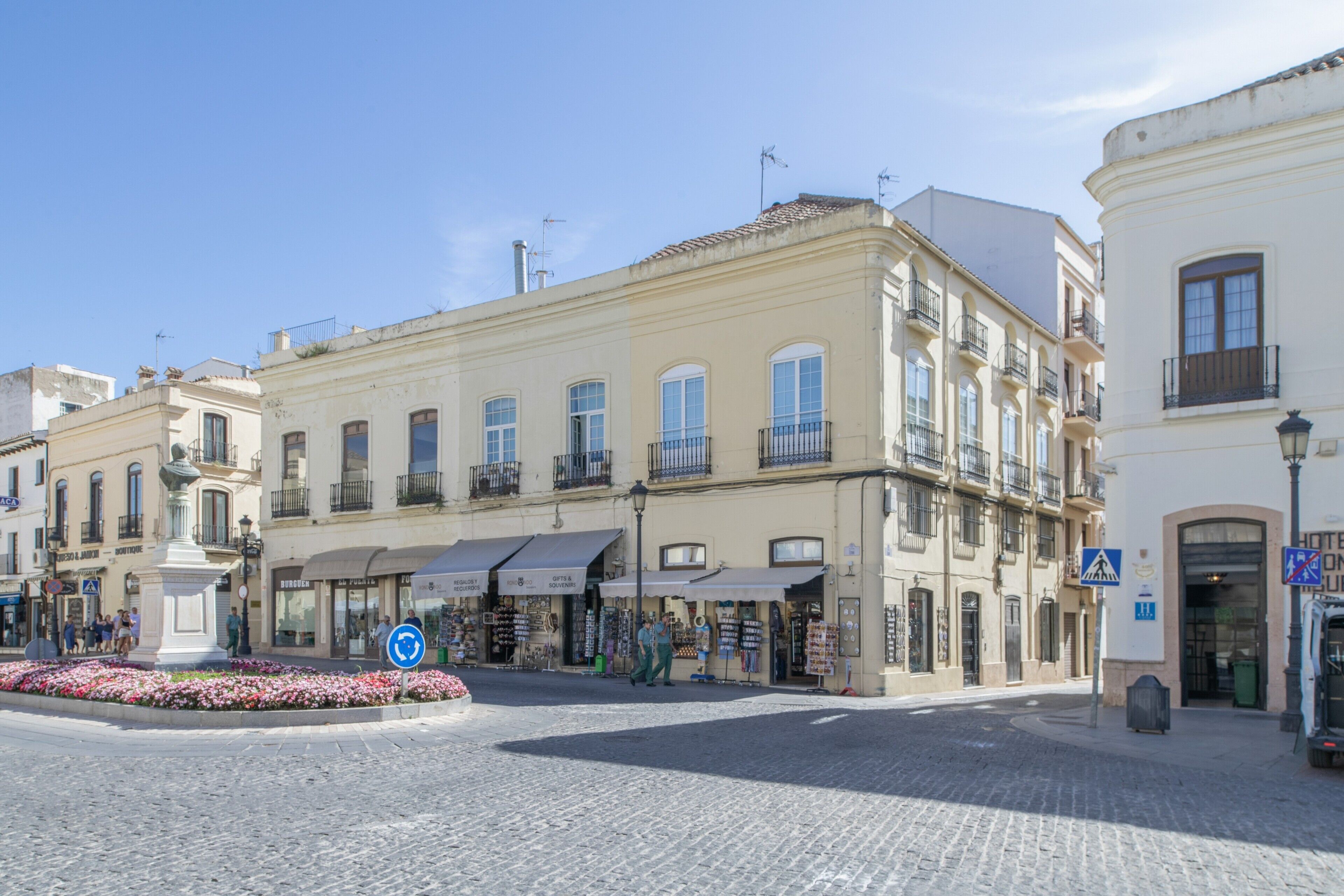 Une rue pavée bordée d’immeubles, un rond-point et une enseigne d’hôtel.