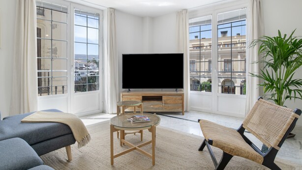 A modern living room with a large TV, comfortable seating, and a view of the city.