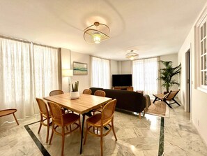 Ein Hotelzimmer mit Esstisch, Stühlen, einer Couch, einem Fernseher und einer Pflanze.