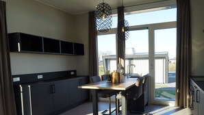 Een moderne keuken met een eethoek, grote ramen en uitzicht op de omgeving.