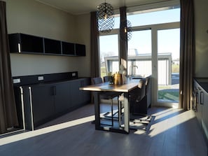 Een moderne keuken met een eethoek, grote ramen en uitzicht op de omgeving.