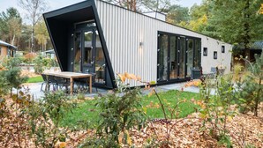 Een modern huis met een uniek, hoekig ontwerp, grote ramen en een patio.