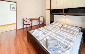 Ein Schlafzimmer mit einem Bett, zwei Stühlen, einem kleinen Tisch und einem Kleiderschrank.