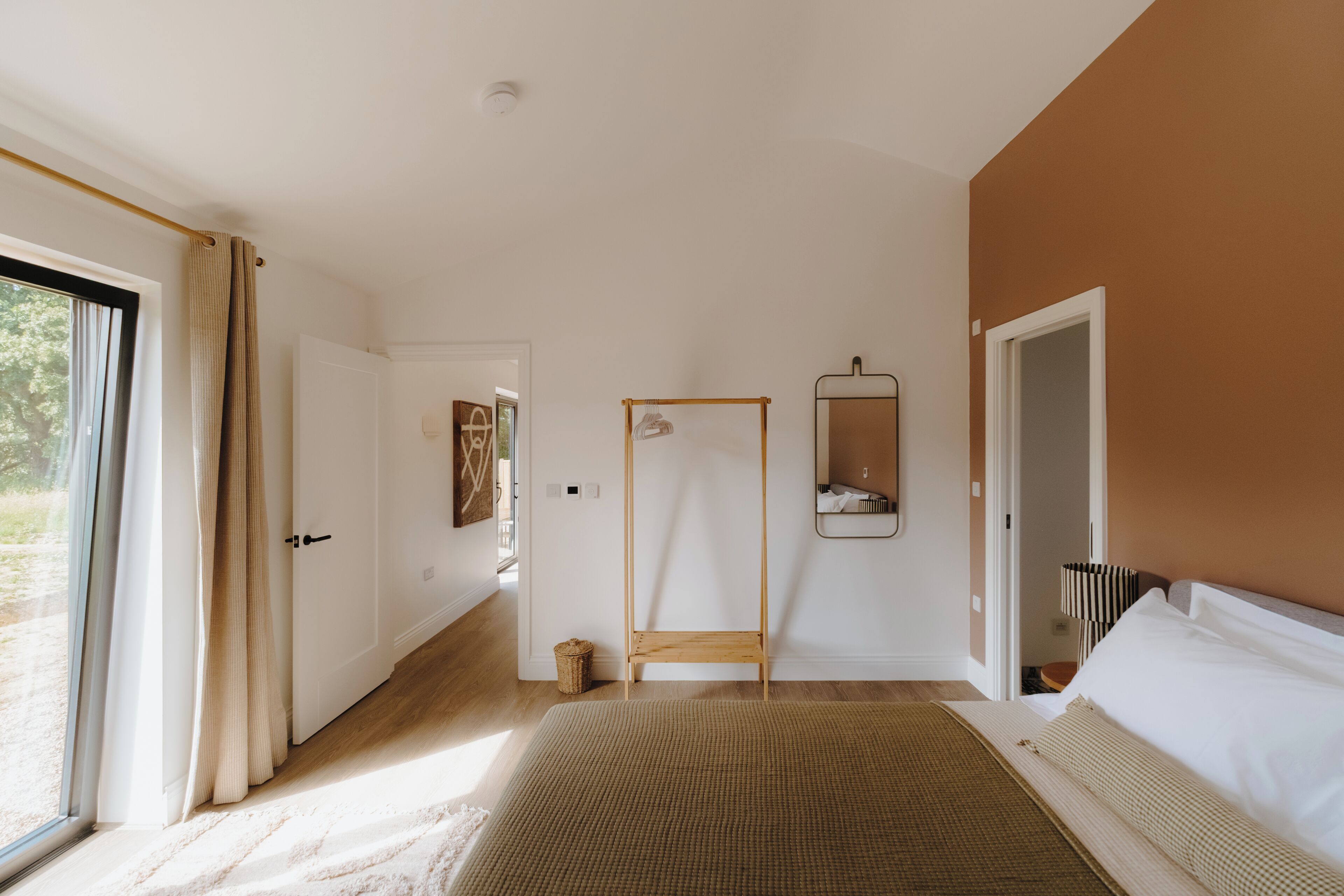 Une chambre à coucher avec un lit, un banc en bois, un miroir et une porte.