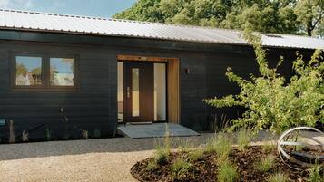 A modern building with a dark exterior, a wooden door, and a gravel driveway.
