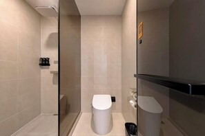 A modern bathroom with a glass shower enclosure, a white toilet, and a small trash bin. - Beifang Langyue Hotel (Beijing Ganjiakou Subway Station) (Beijing)