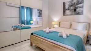 Una camera d'albergo con un letto grande, uno specchio, un quadro appeso al muro e un comodino con una lampada.