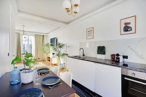 Eine moderne Küche mit weißen Schränken, einer Marmor-Spritzschutzwand und einem eingebauten Backofen.