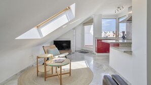 Un moderno loft con tragaluces, una cocina con detalles rojos, un comedor con mesa redonda y una sala de estar con televisor de pantalla plana.