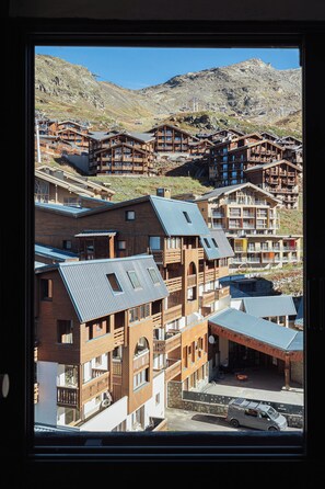 A mountain resort with wooden buildings, ski lifts, and a parking area. - Cimes de Caron Val Thorens (Val Thorens)