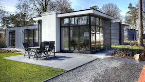 A modern house with a patio, a dining area with chairs, and a large glass window. - Holiday Home in Belfeld With Terrace (Belfeld)