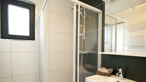 A modern bathroom with a glass shower enclosure, a white sink, and a mirror above it. - Holiday Home in Belfeld With Terrace (Belfeld)