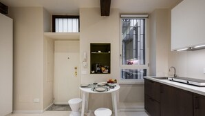 Une cuisine compacte comprenant une table à manger, des tabourets, une fenêtre et une étagère intégrée.