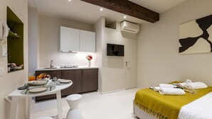 Une chambre d’hôtel moderne comprenant un lit, une table à manger, un coin cuisine et une salle de bain.