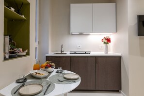 Eine moderne Küche mit weißer Arbeitsplatte, dunklen Holzschränken, einem eingebauten Backofen und einer kleinen Essecke mit Tisch für zwei Personen.