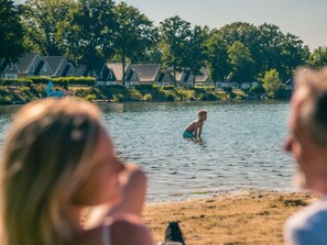 Blick auf einen See mit einer Reihe von Häusern im Hintergrund.
