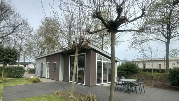 Moderni, yhden kerroksen omakotitalo, jossa on patio, ruokailutila ja suuri ikkuna.