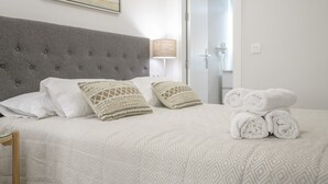 Ein Hotelzimmer mit Bett, Kissen, einer Lampe und einem Stapel Handtücher.