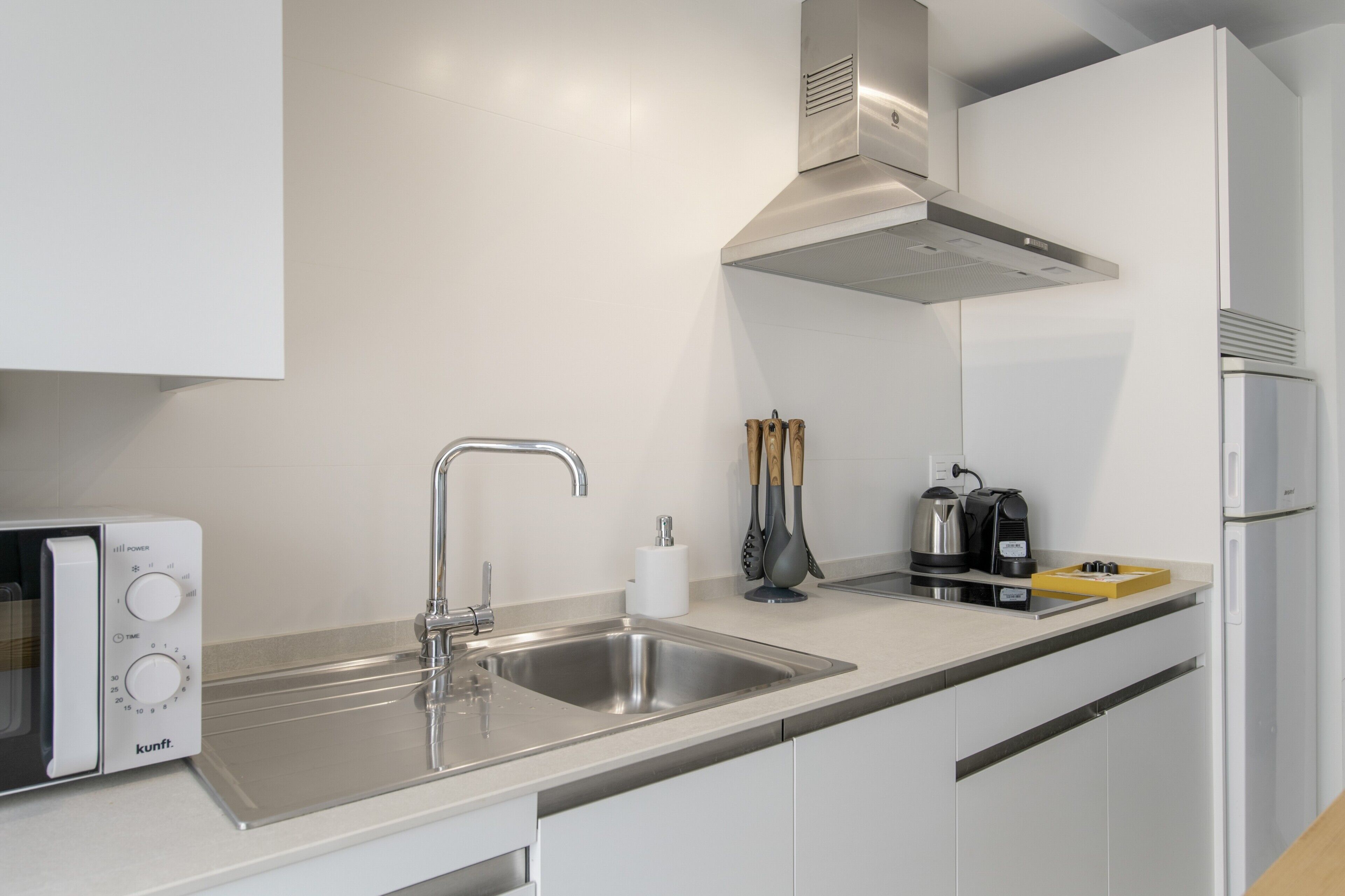 A modern kitchen with a built-in microwave, stainless steel sink, and a coffee maker.
