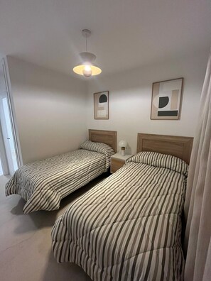 Ein Schlafzimmer mit zwei Betten, einem Nachttisch, einer Lampe und einer Deckenleuchte.